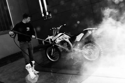 Side view of young man with motorcycle against blurred background