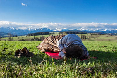 Young man sleeping on green sunny field