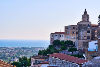 Buildings by sea against clear sky