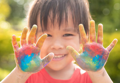 Close-up portrait of girl showing multi colored hands