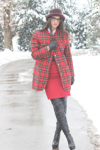 Full length portrait of young woman standing in snow