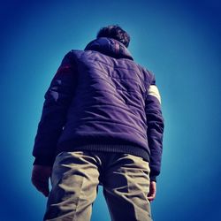 Low section of man photographing against clear blue sky