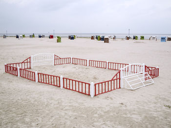 Hooded chairs on beach against sky