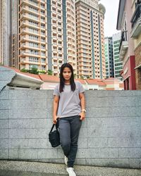 Full length portrait of woman standing against buildings