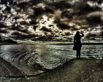 People standing on beach against cloudy sky