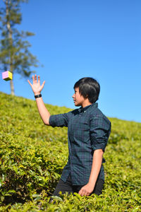 Rear view of boy on field against clear sky