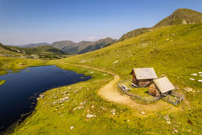Scenic view of two cabins by a lake and mountains against sky.