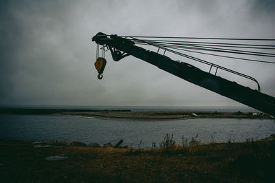 Crane at lakeshore against cloudy sky at dusk