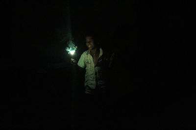 Young woman standing against illuminated lights at night