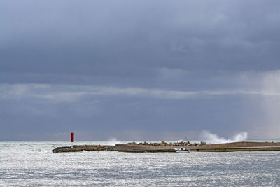 Lighthouse by sea against sky