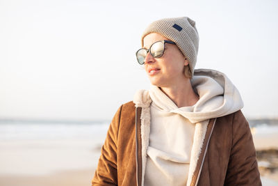 Portrait of young woman wearing hat against sea