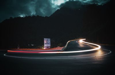 Light trails on road in city against sky at night