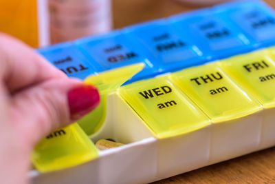 Cropped hand of woman taking pills in container with text on table