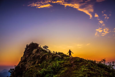 Silhouette man standing on cliff against sky during sunset