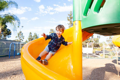 Modern colorful kids playground - swings, slides, steps and ladders. little boy on swing and slide.