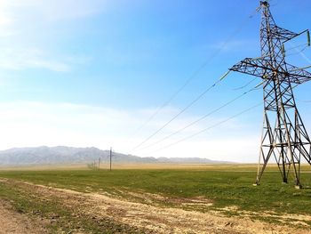 Low angle view of electricity pylon on field against sky