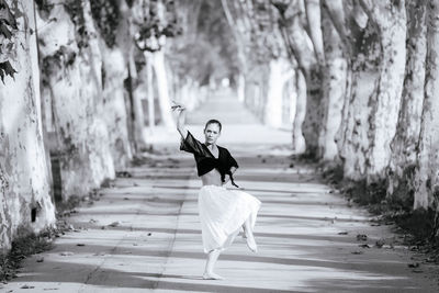 Full length of woman with arms raised on footpath