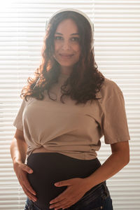 Portrait of smiling young woman standing against wall