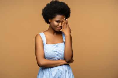 Young woman standing against yellow background