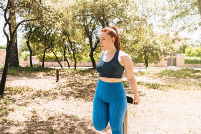 Side view of woman standing against trees