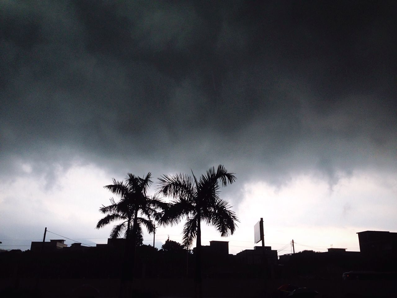 silhouette, sky, cloud - sky, cloudy, tree, low angle view, building exterior, built structure, overcast, weather, architecture, cloud, dusk, nature, storm cloud, beauty in nature, house, tranquility, outdoors, palm tree