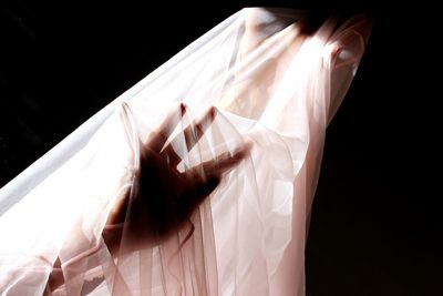 Cropped hand hand of woman with textile against black background