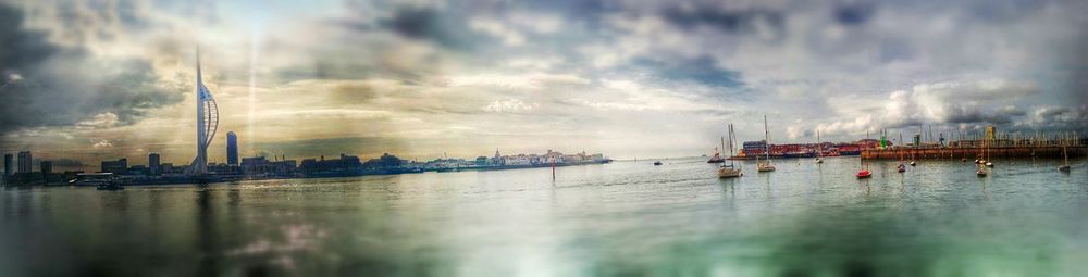 Boats moored at harbor against cloudy sky