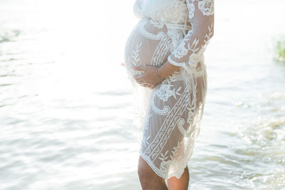 Midsection of woman standing at beach against sky