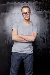 Portrait of young man standing against wall