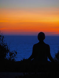 Silhouette man sitting by tree against sky during sunset