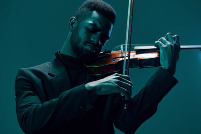 Midsection of man playing violin against black background