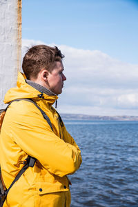 Side view of man looking at sea against sky