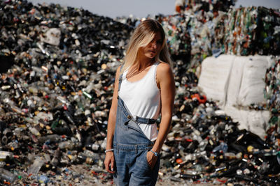 Young woman standing against garbage