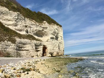 Rock formation on beach against sky