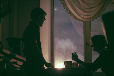 Silhouette of people by table at home