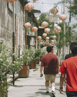 Rear view of men walking on street in city