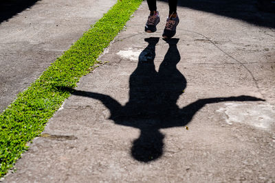 Low section of woman with shadow on road