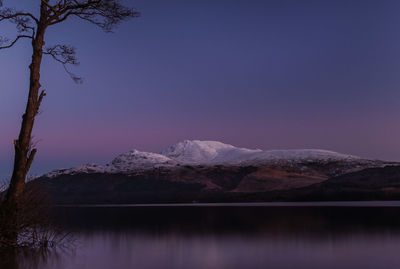 Scenic view of lake and mountains against clear blue sky