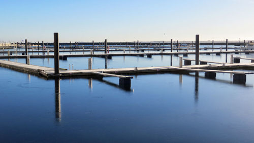 Reflection of wooden bridge on river against clear sky