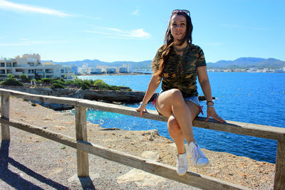 Girl on fence posing on vacation enjoying the blue color of summer in ibiza in the balearic islands