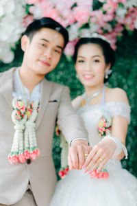 Portrait of smiling bride and groom showing rings during wedding