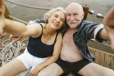 Happy senior couple taking selfie while sitting on houseboat