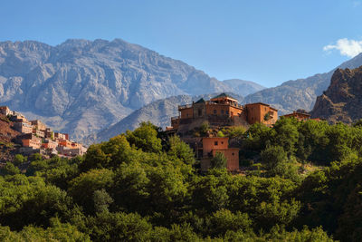 Houses and trees by mountains against sky