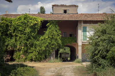 House by trees and buildings against sky