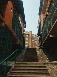 Low angle view of staircase amidst buildings against sky