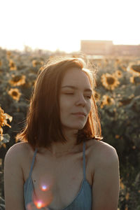 Beautiful woman looking away against sunflower plants at farm