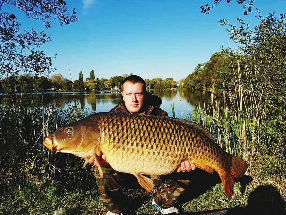 YOUNG MAN FISHING IN LAKE AGAINST TREES