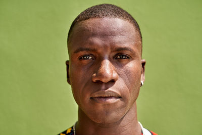 Content african american male in casual wear looking at camera against green background on street