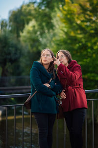 Sister pointing while standing by railing in city