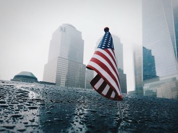 Low angle view american flag by buildings during rainy season